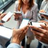 Oameni interacționând cu dispozitive digitale, lumini de ecran.